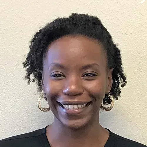 A woman wearing hoop earrings and a black shirt is smiling for the camera.