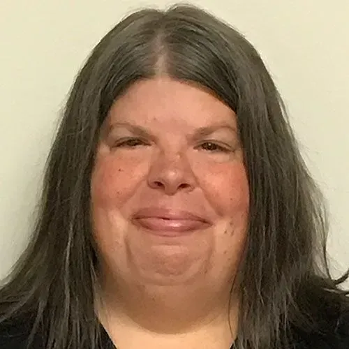 A woman with long hair is smiling for the camera.