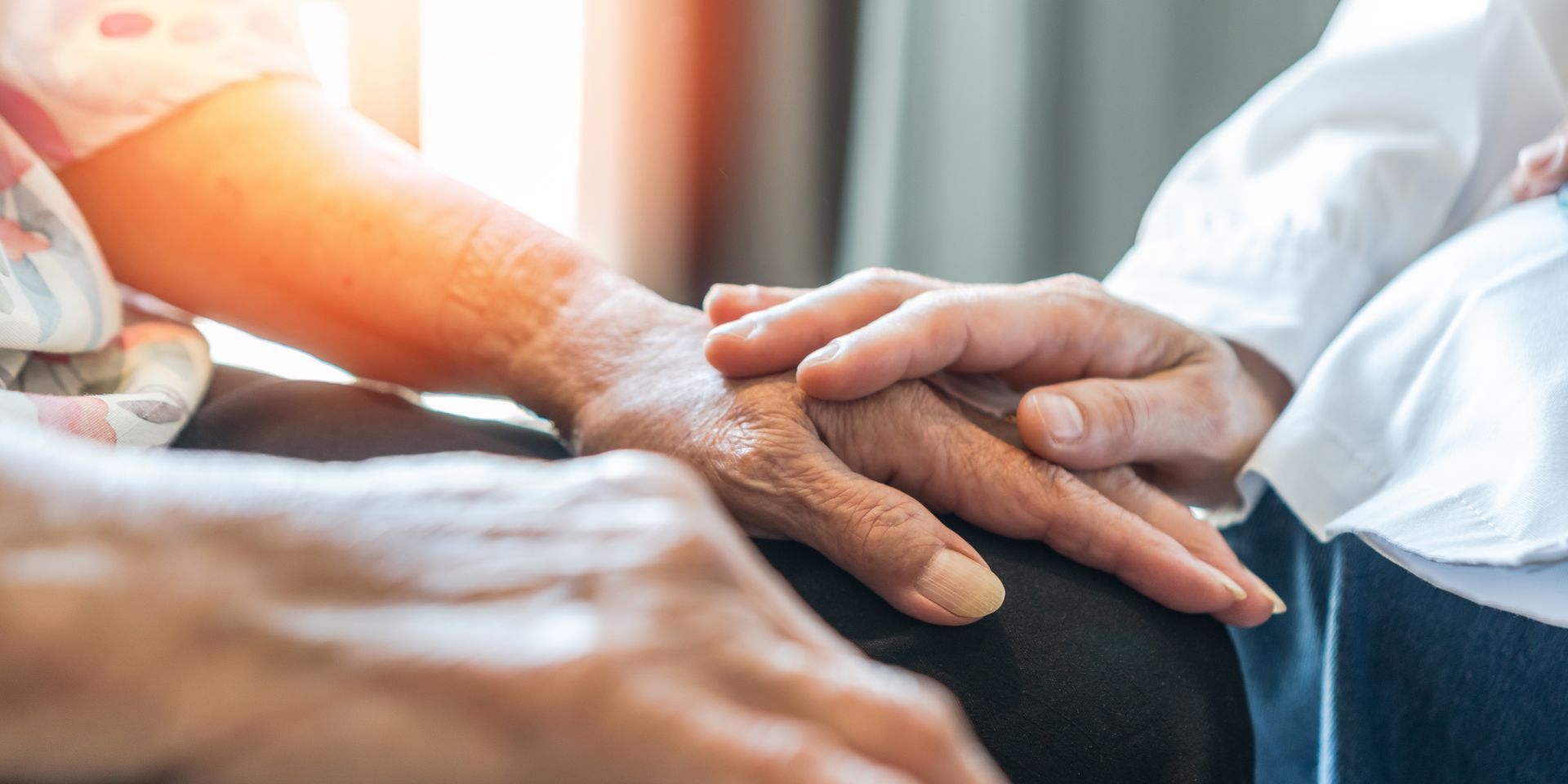 Two hands resting on top of each other, one hand is touching the other in a comforting manner.