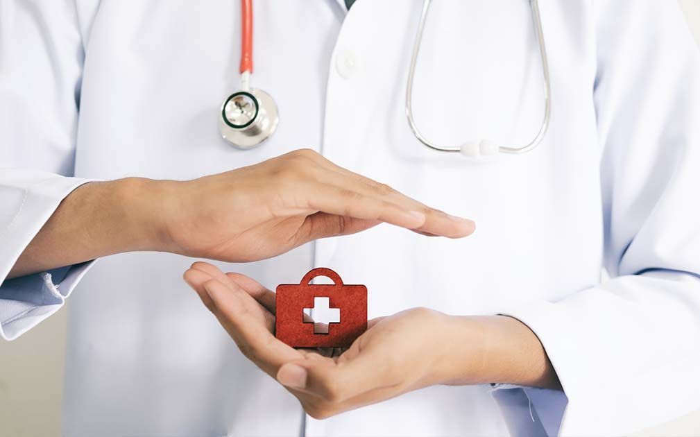 Doctor holding a medical kit icon, hands protecting, stethoscope visible.