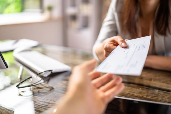 Handing over a check at a table in a bright office setting