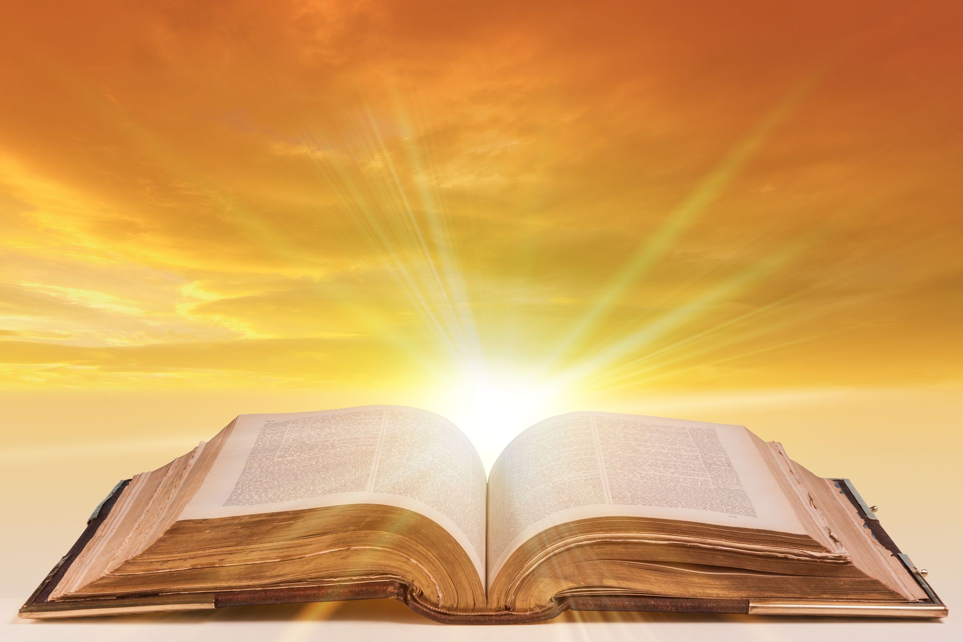 Open book with bright light emanating from it, against an orange sky.