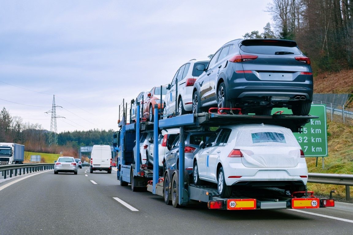 A semi truck driving on the highway with multiple vehicles loaded for door-to-door transport service
