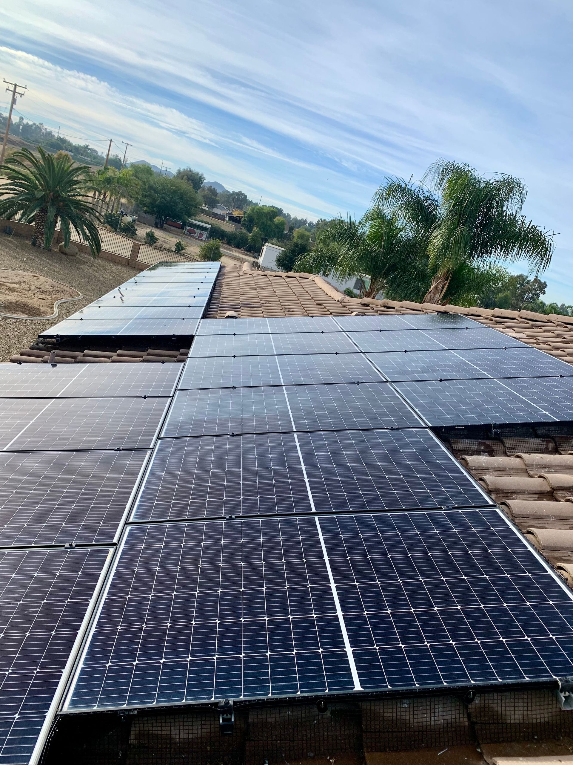 A row of solar panels are sitting on top of a tiled roof.