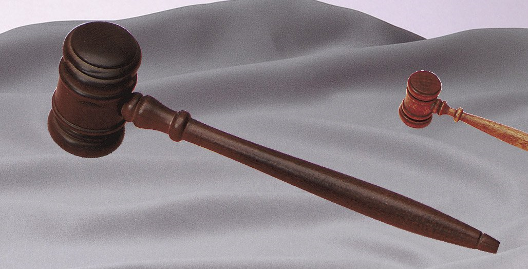 A wooden judge 's gavel is laying on a white cloth