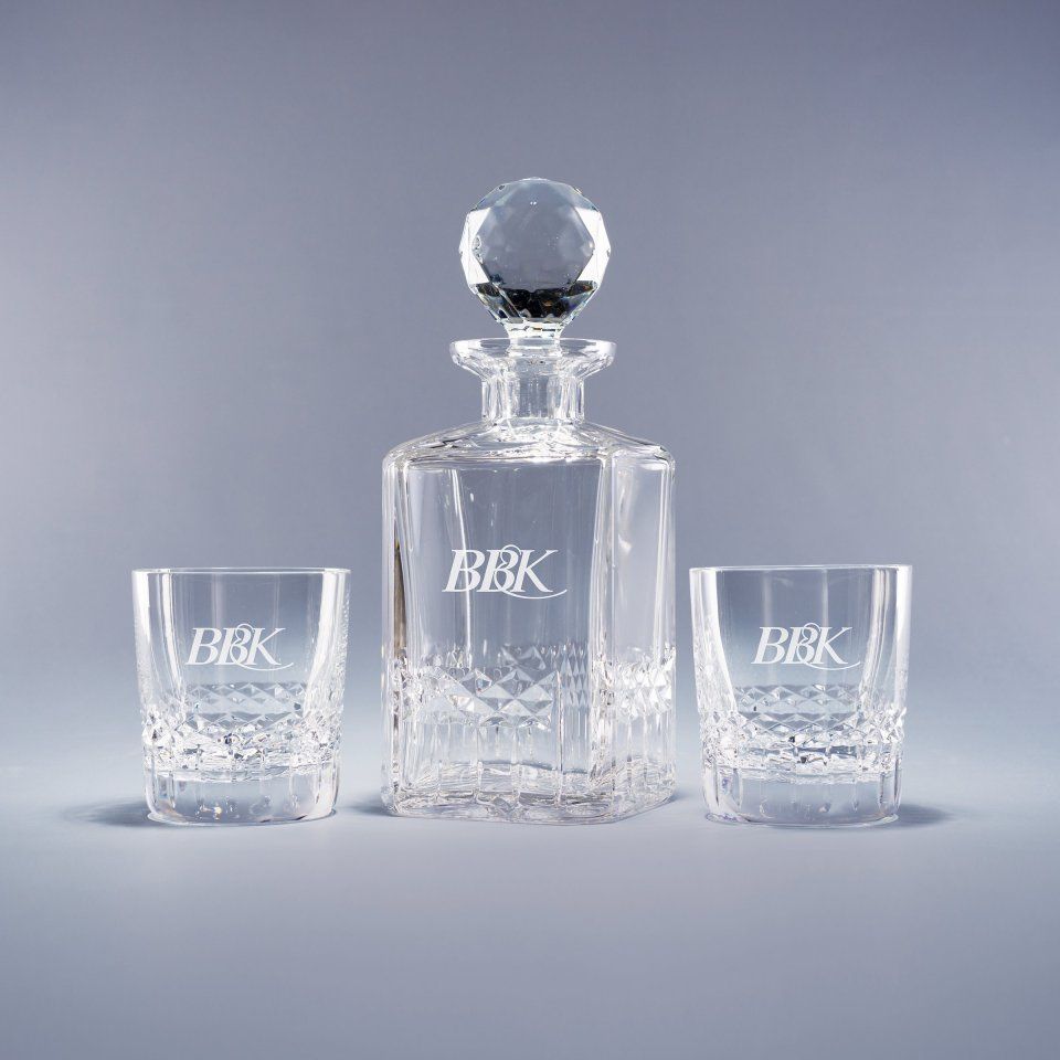 A decanter and two glasses with the letters bbk on them