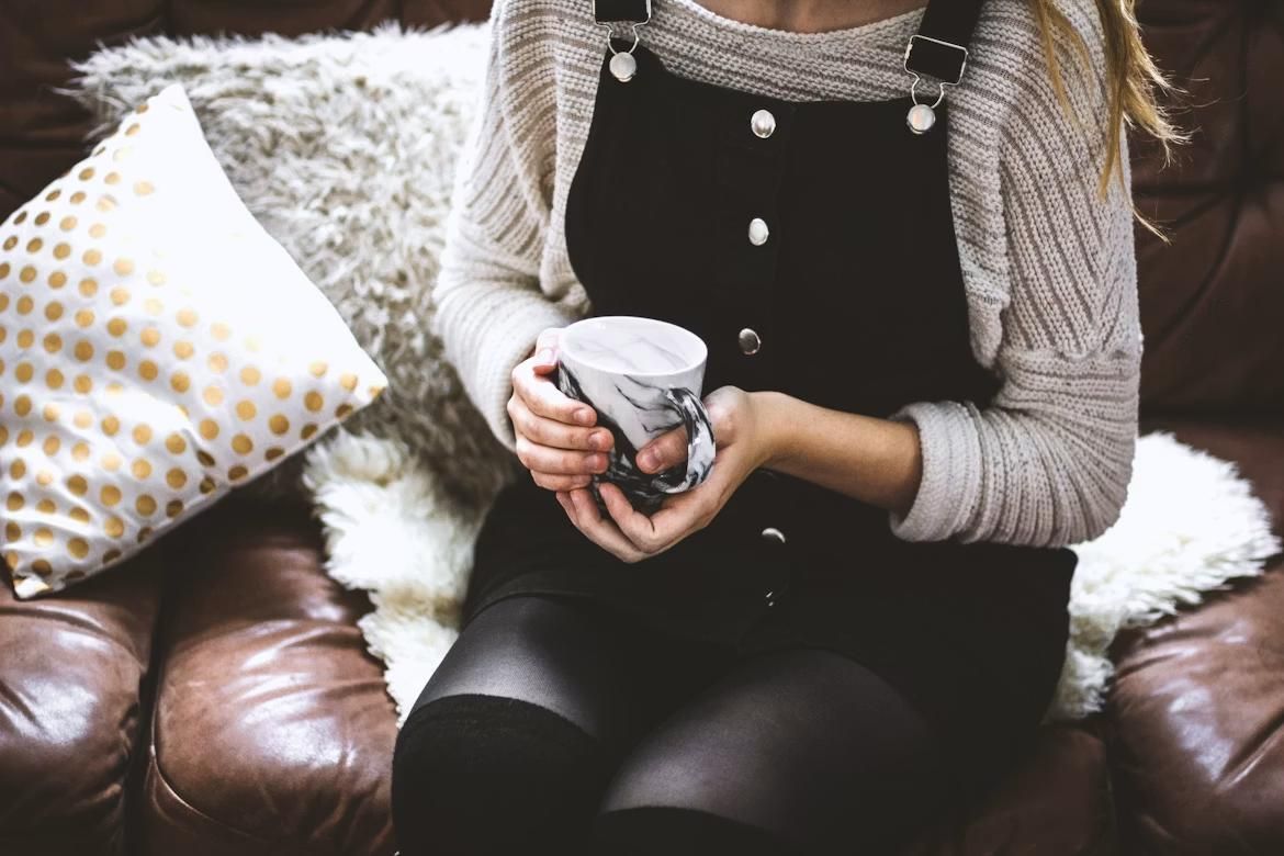 A woman looks cozy on a couch.