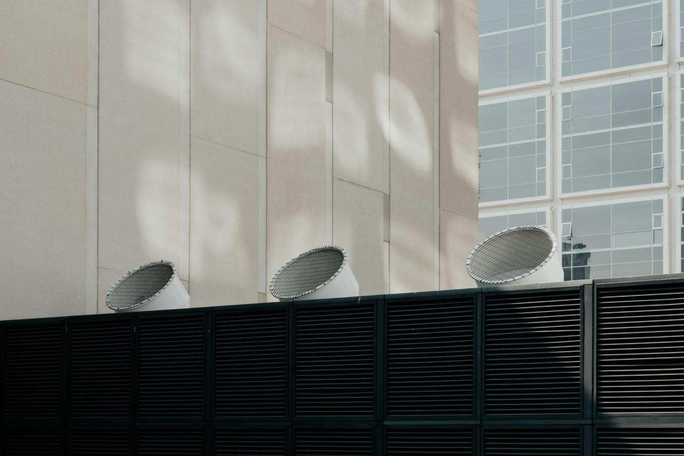 External part of a ventilation system on the roof of a modern building near a concrete wall.