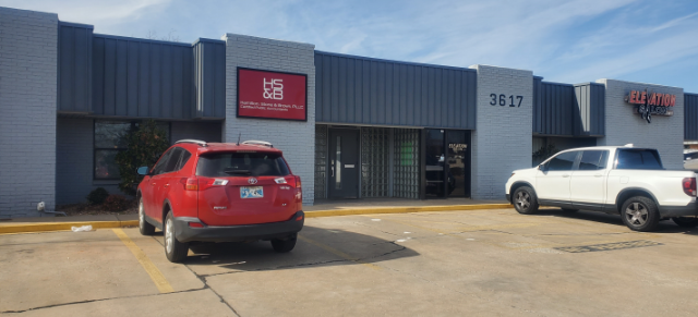A red suv and a white truck are parked in front of a building.