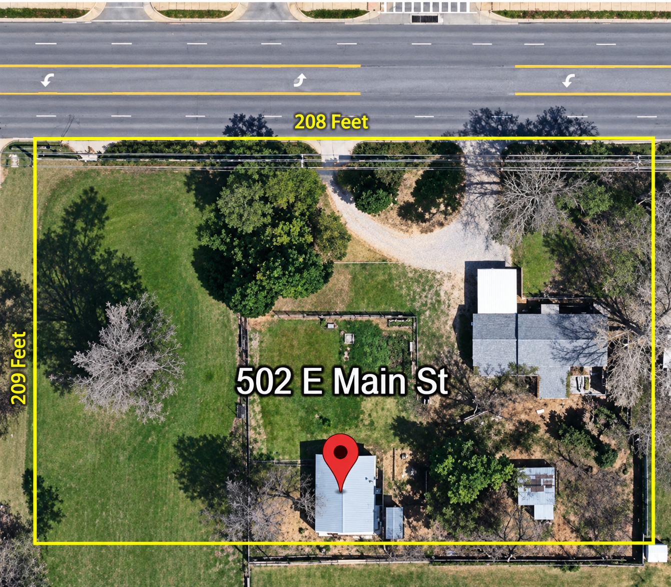 Aerial view of the property at 502 E Main St, showing a large rectangular lot measuring approximately 208 feet by 209 feet, with a house, additional structures, trees, lawn, driveway, and surrounding roadway outlined in yellow.