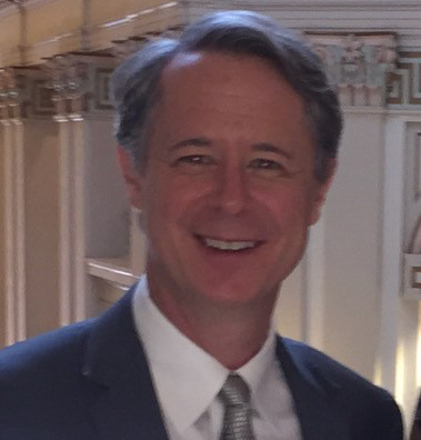 A man in a suit and tie smiles for the camera