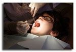 Person in dental chair, mouth open, dentist examining teeth with instruments.