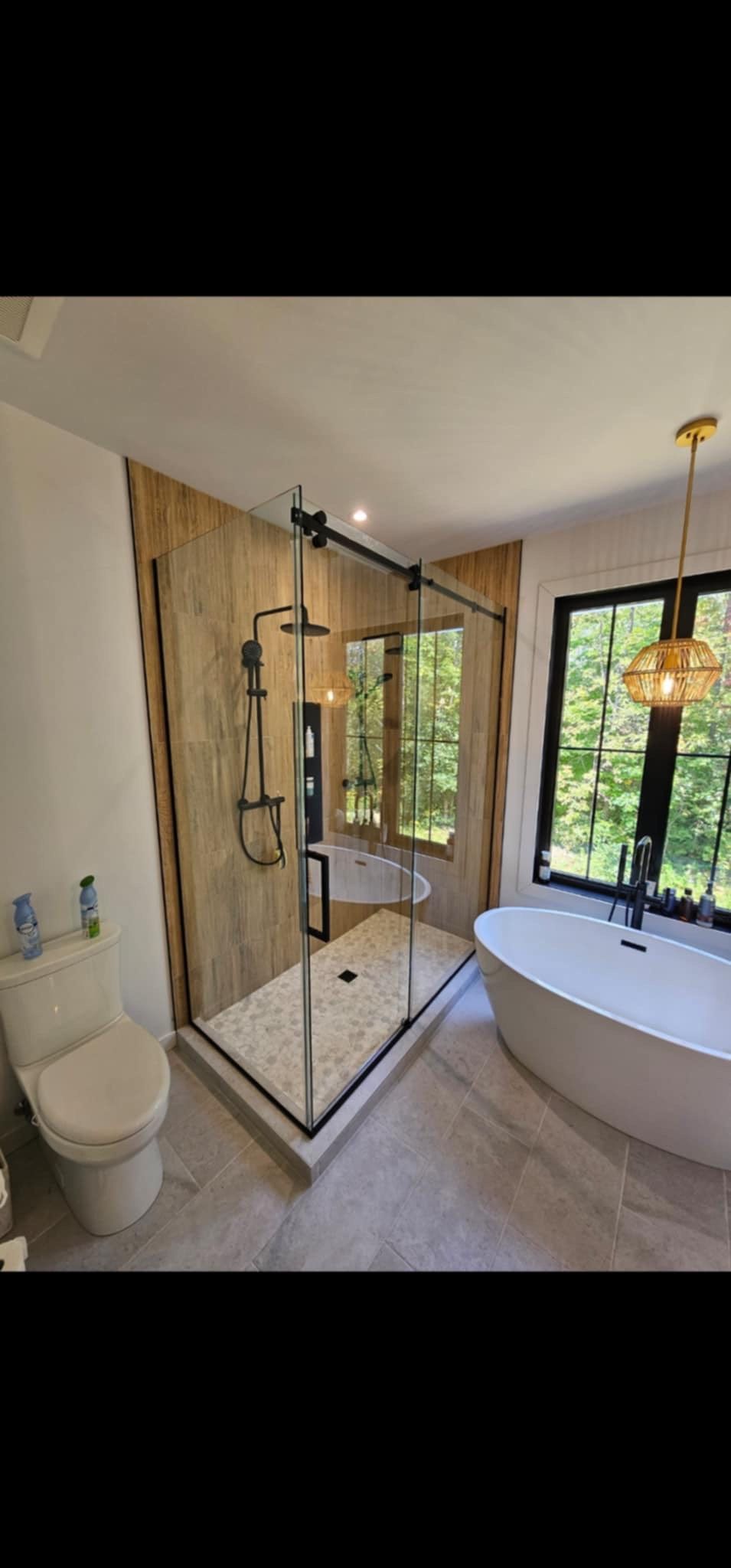 Une salle de bain avec baignoire, WC, douche et fenêtre.