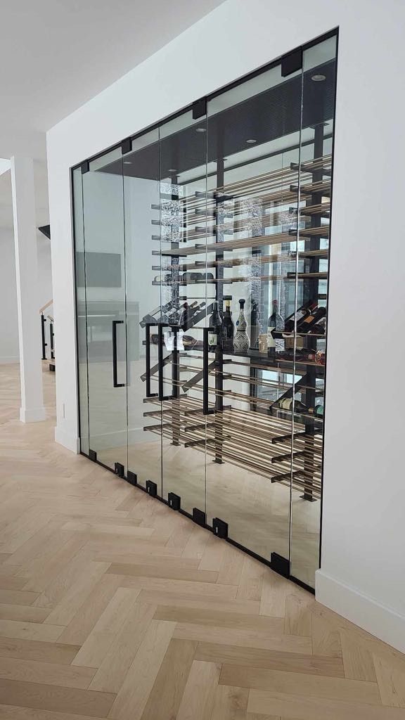 Une cave à vin avec portes coulissantes en verre et un sol à chevrons.