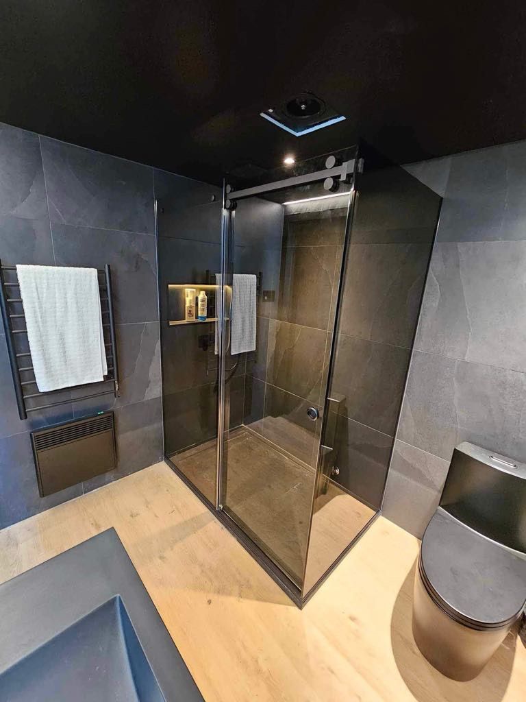 Une salle de bain avec douche à l'italienne, WC, lavabo et miroir.