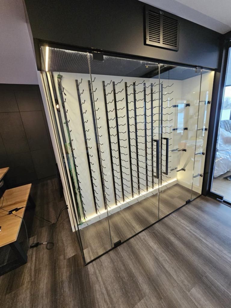 Une cave à vin avec une paroi vitrée et de nombreux casiers à vin.