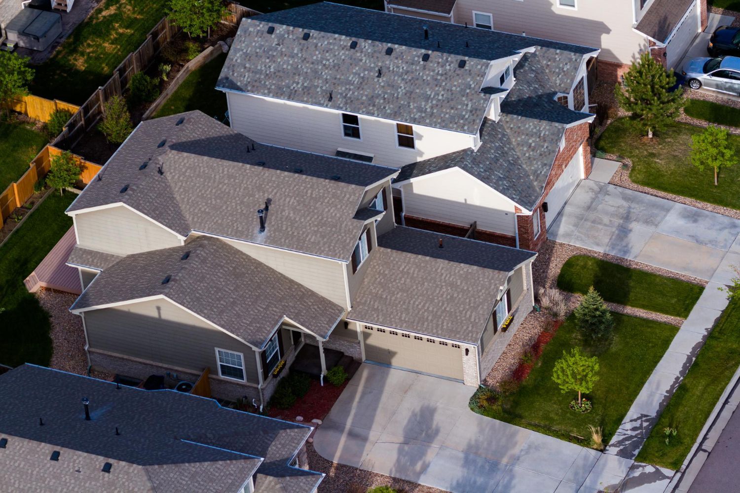 Aerial view of a suburban neighborhood with several gray-roofed houses and lawns.