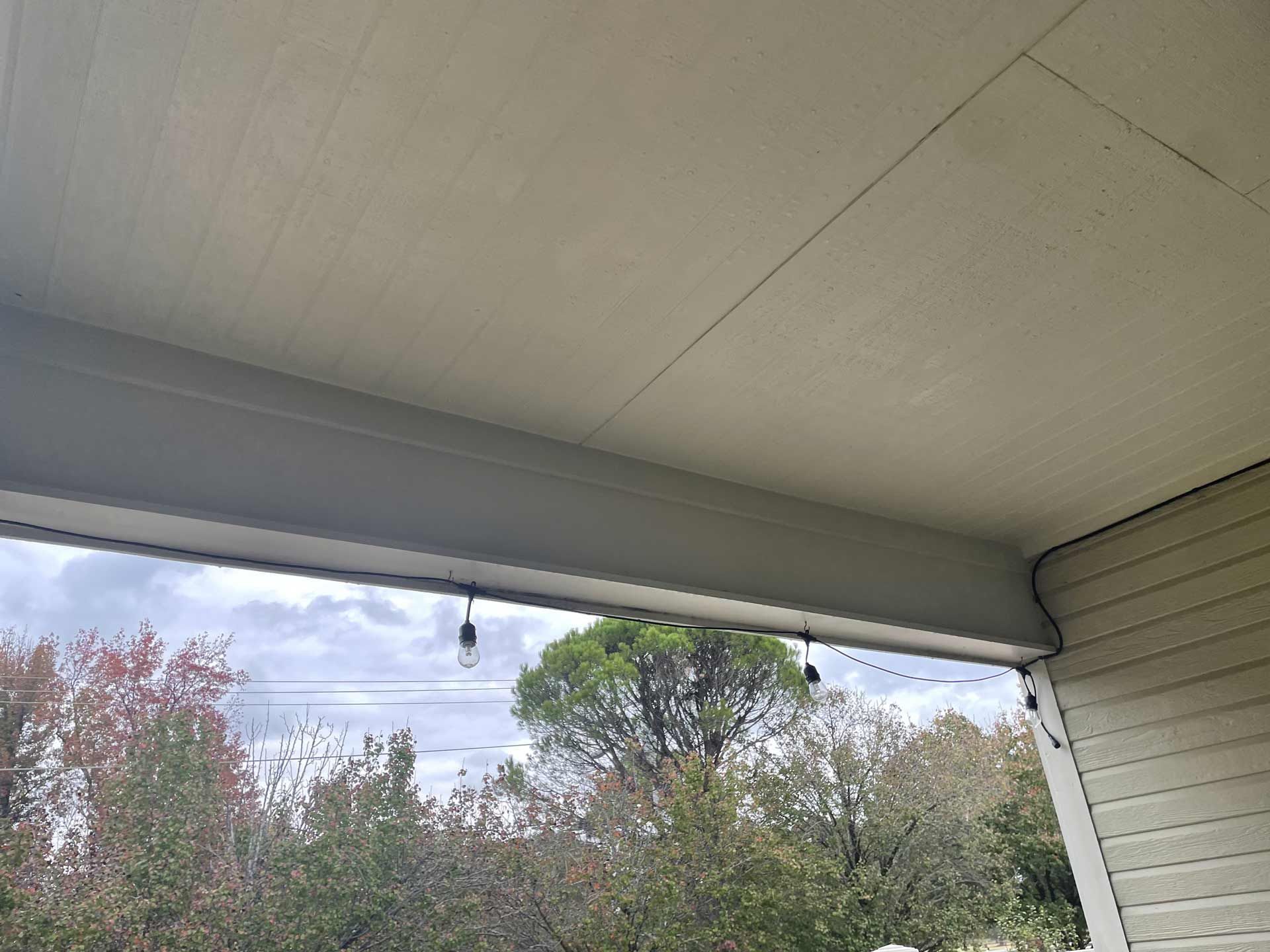 The ceiling of a porch with lights hanging from it and trees in the background