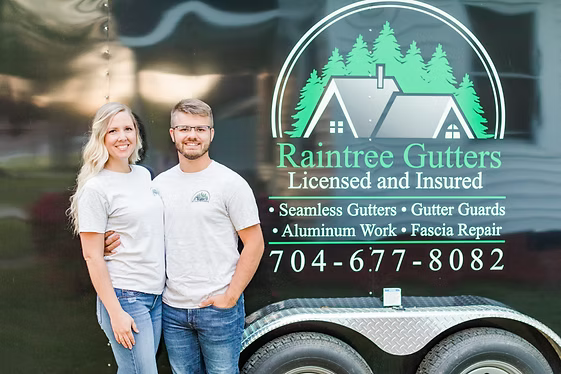 A couple stands beside a trailer with a