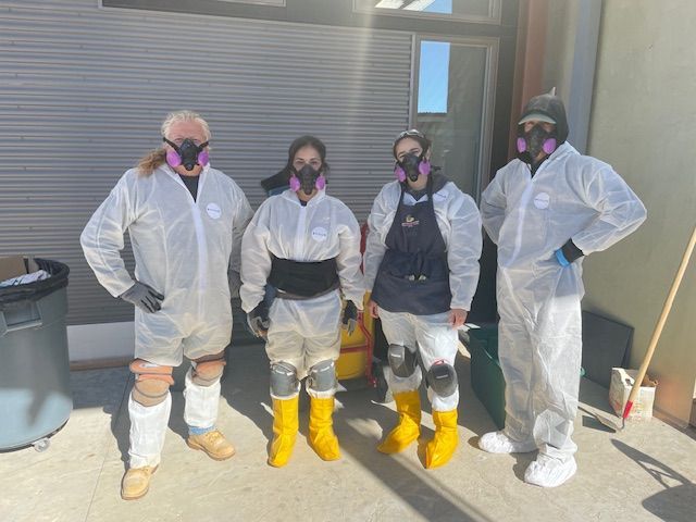 A group of people wearing protective suits and masks are standing next to each other.