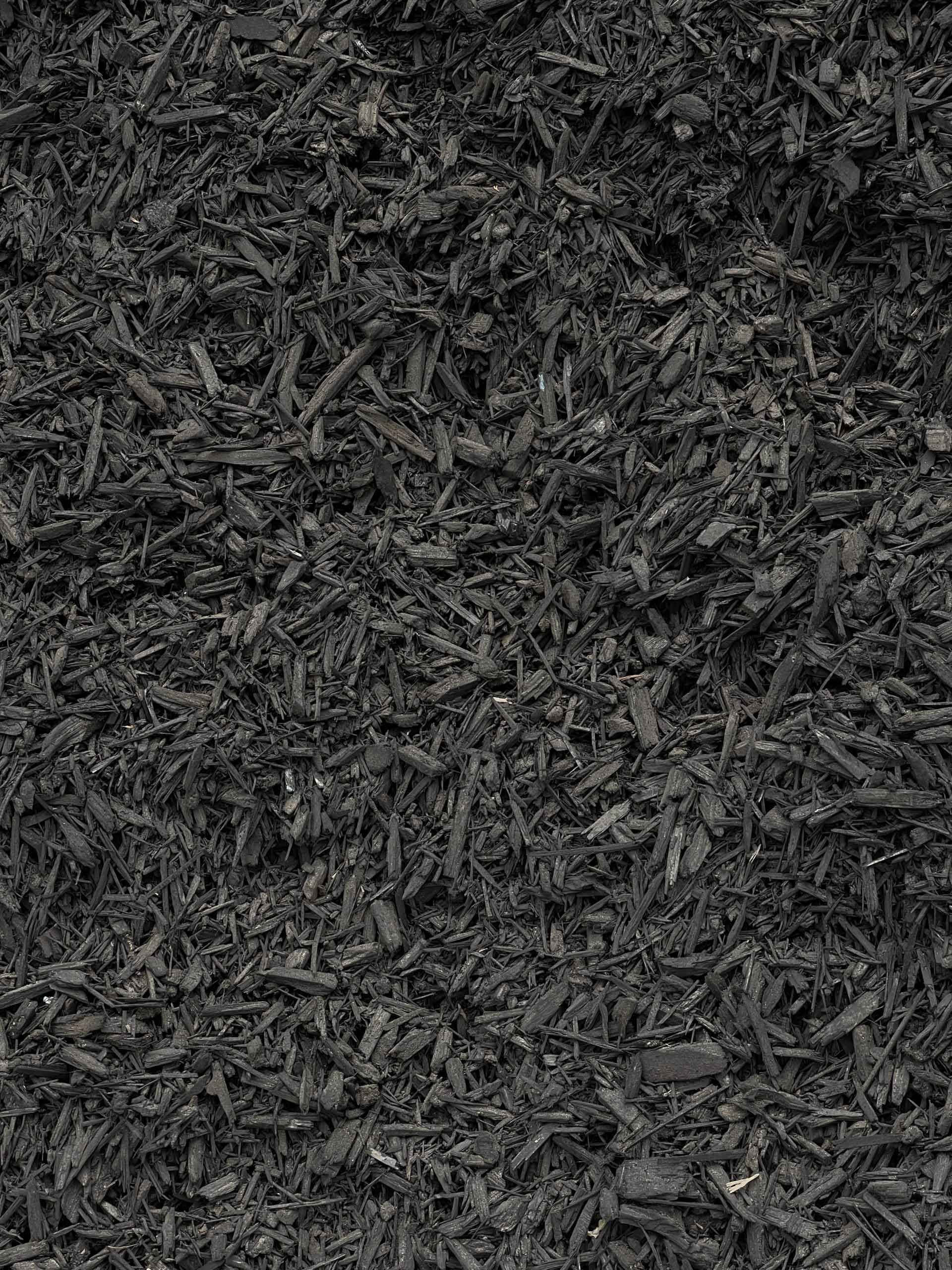 A pile of black mulch is sitting on the ground.