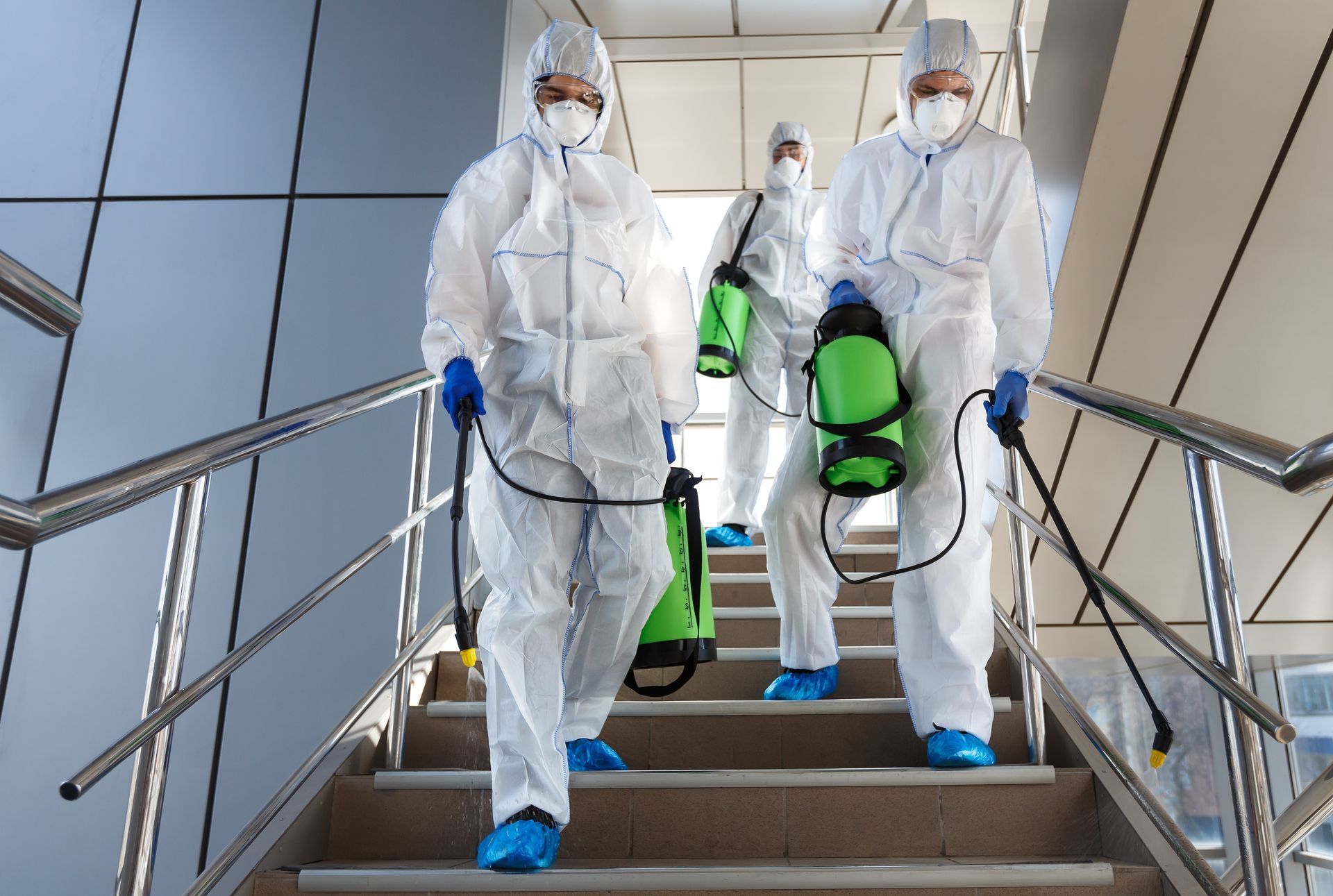 A group of people in protective suits are disinfecting stairs.