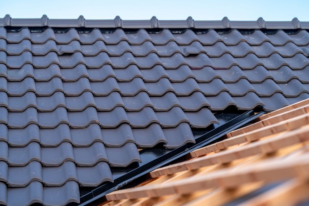 Blue roof tiles with a damaged section near the edge of a wooden roof frame