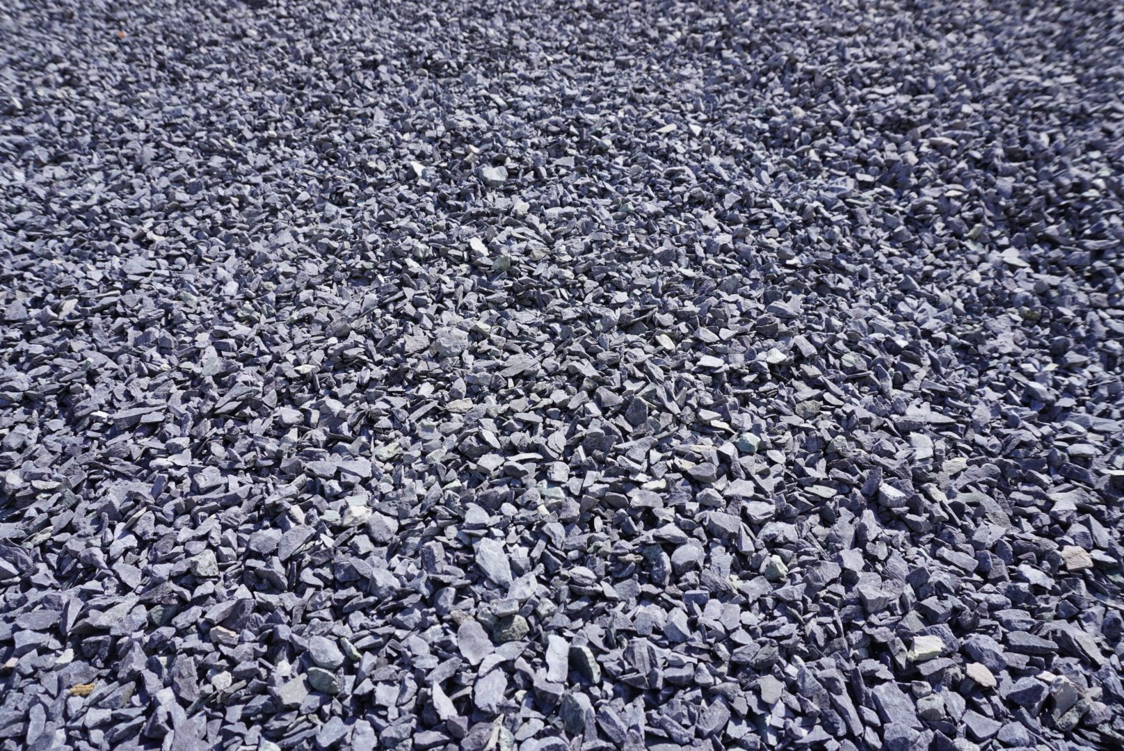 Close-up of a rocky gravel surface with gray and purple stones scattered across the ground