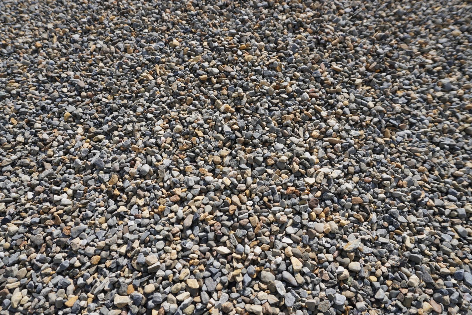 Close-up of a gravel surface with small gray, tan, and brown stones.