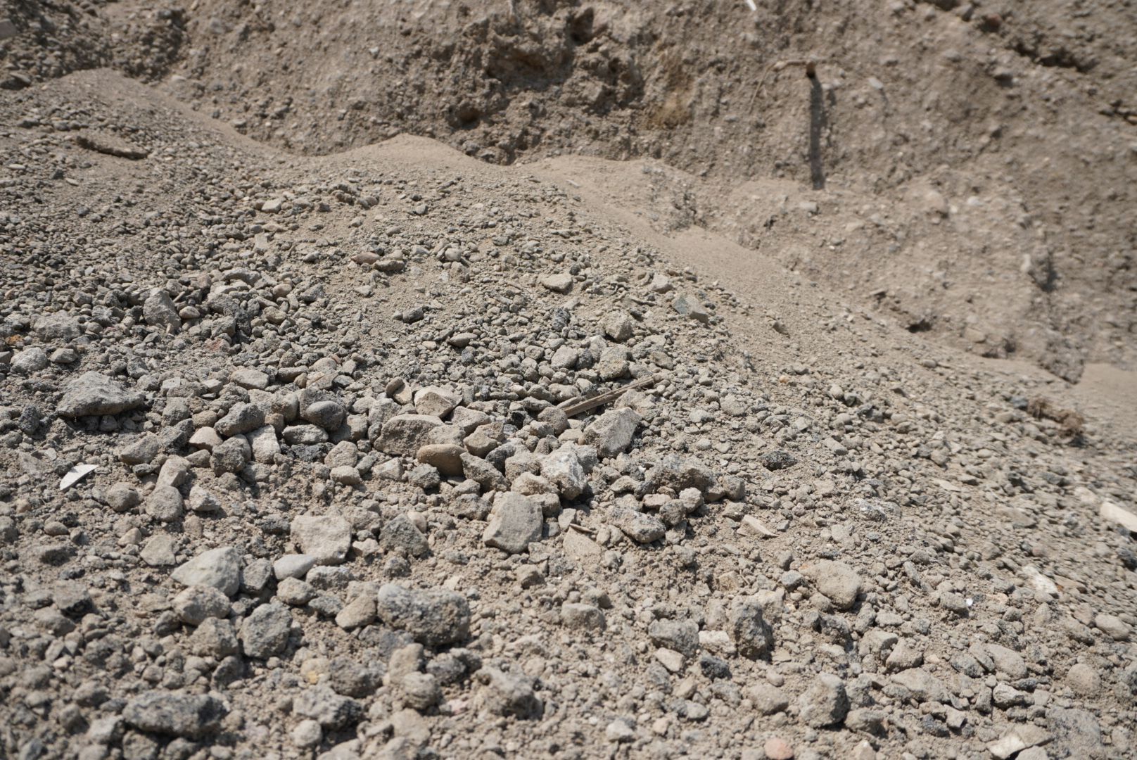 Pile of gray rocks and gravel in a dirt quarry or construction site