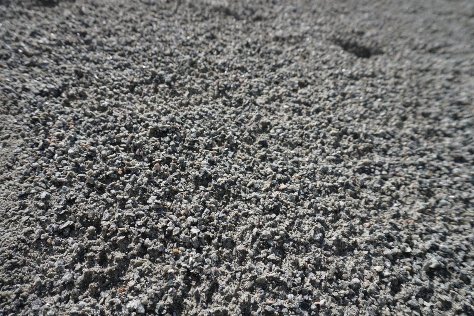 Close-up of rough gray gravel or crushed stone filling the frame