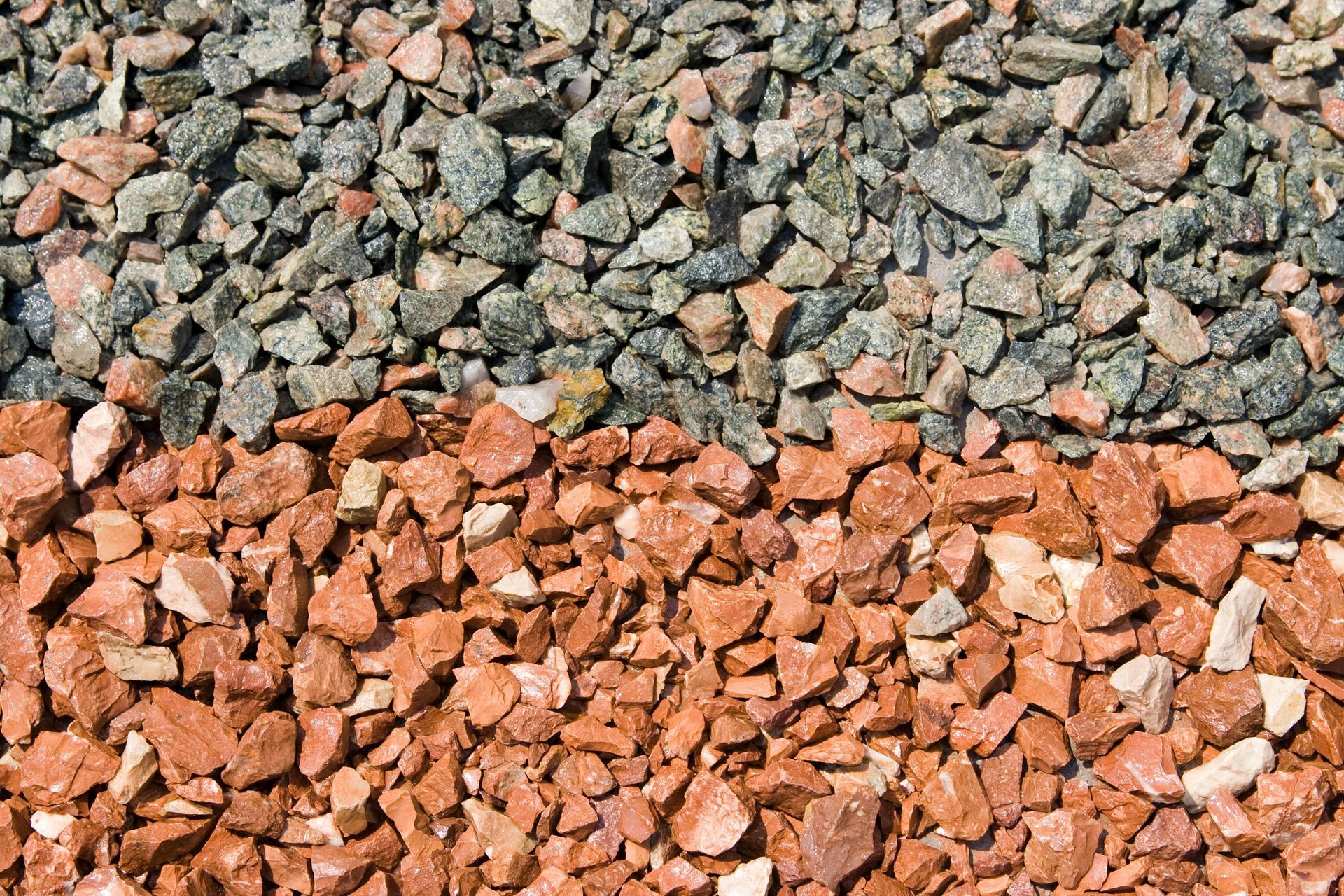 Two piles of crushed stone, gray on top and reddish-orange on bottom
