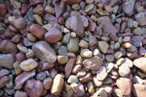 Pile of multicolored pebbles and small rocks, mostly purple, brown, and tan.