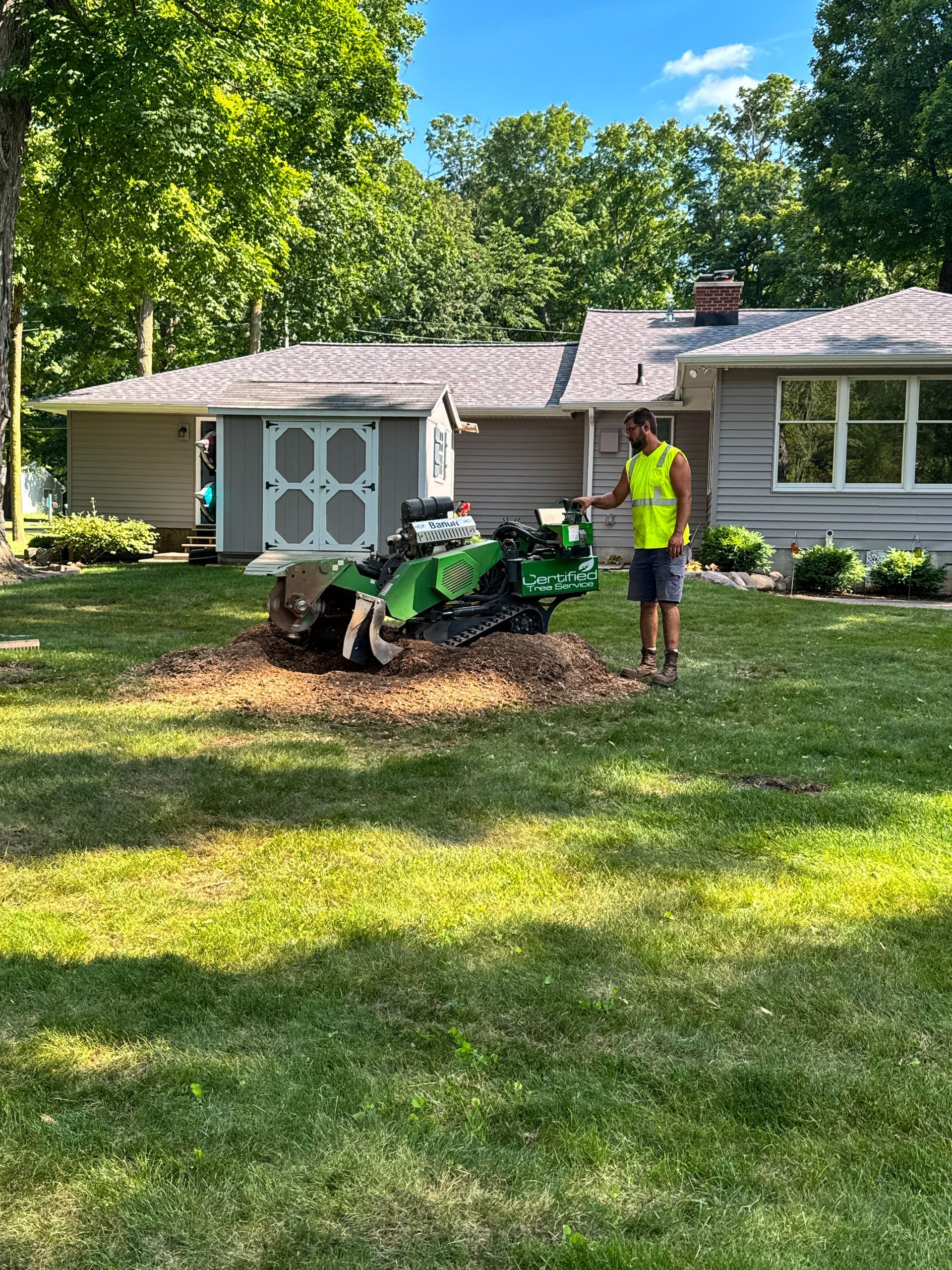 A man is using a stump grinder to remove a tree stump.