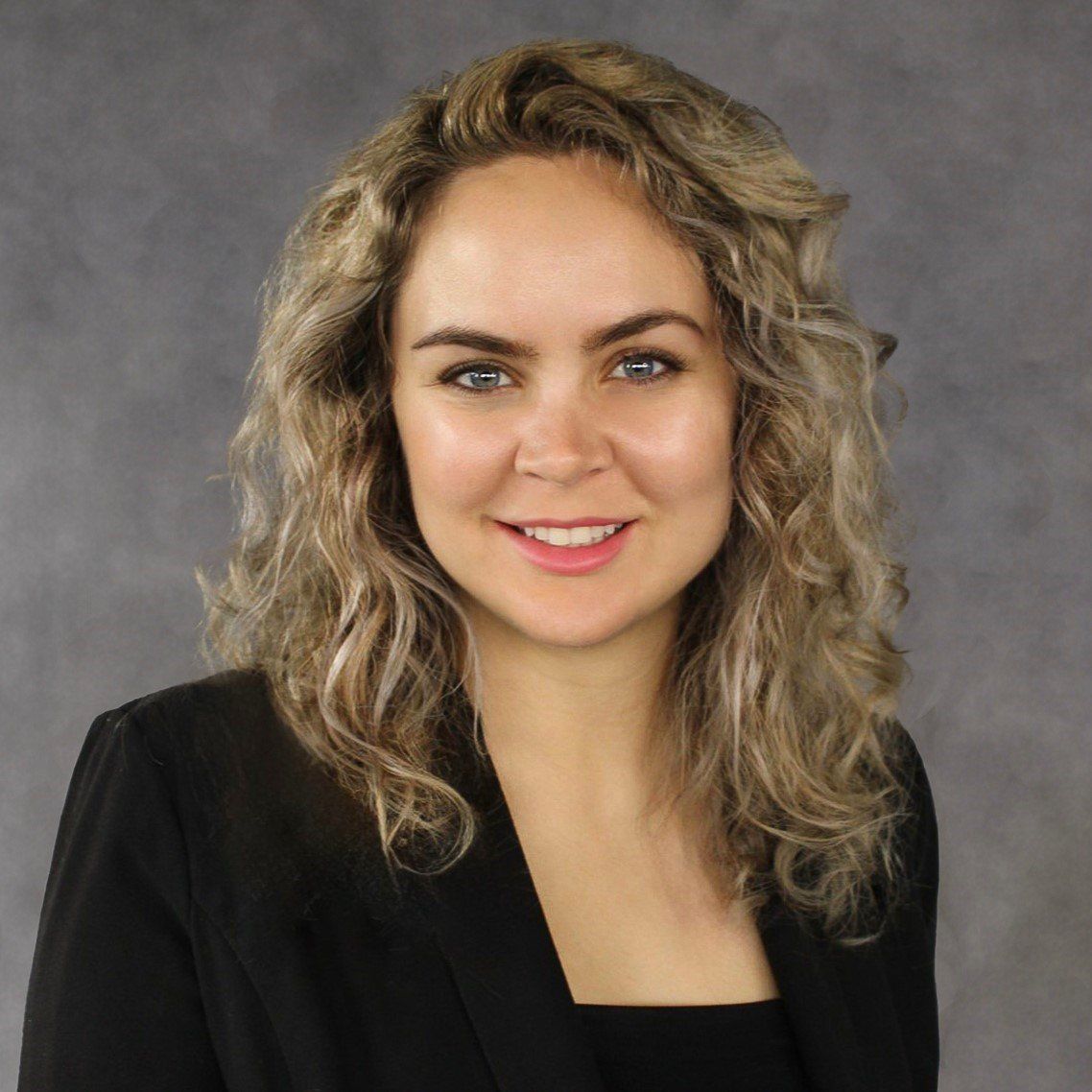 The woman is wearing a black jacket and smiling for the camera.