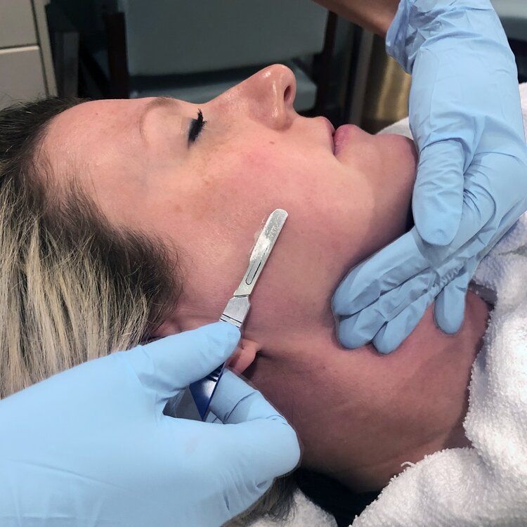 A woman is getting her face shaved with a razor