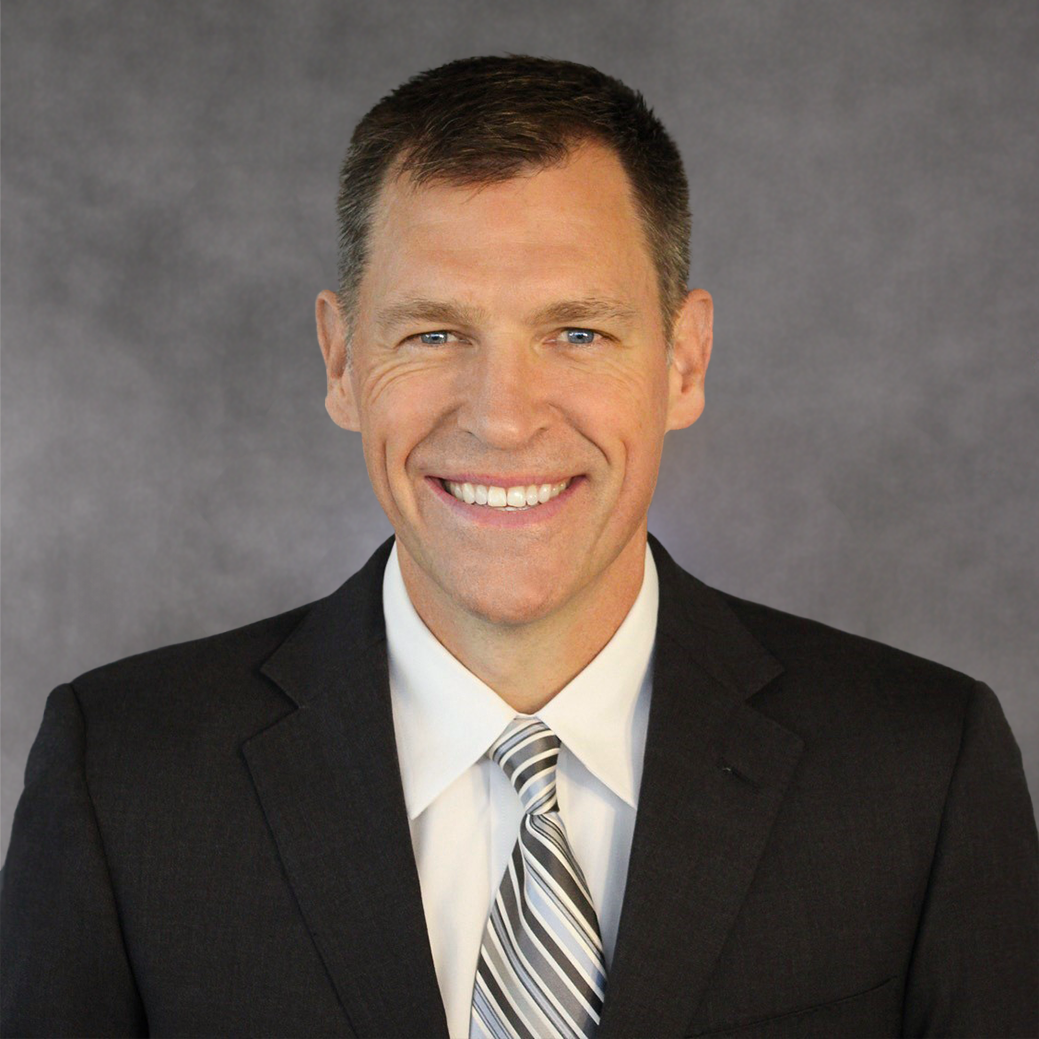 A man in a suit and tie is smiling for the camera