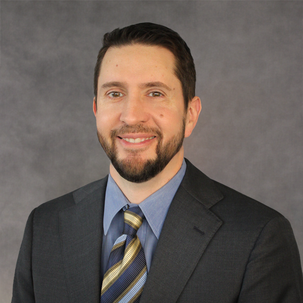 A man in a suit and tie is smiling for the camera