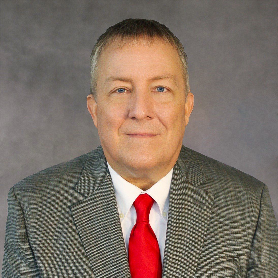 A man in a suit and tie is smiling for the camera