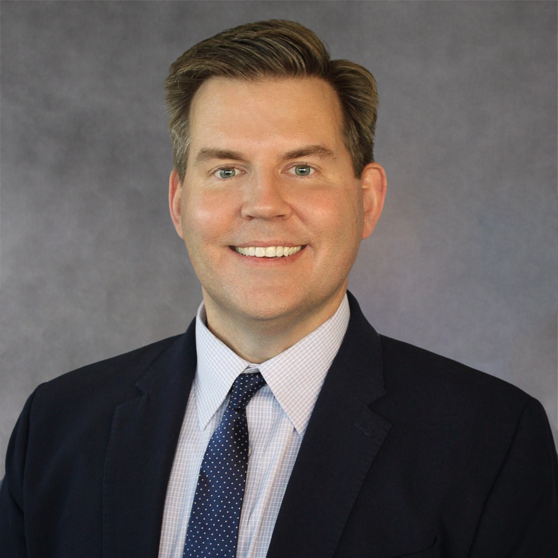 A man in a suit and tie is smiling for the camera.