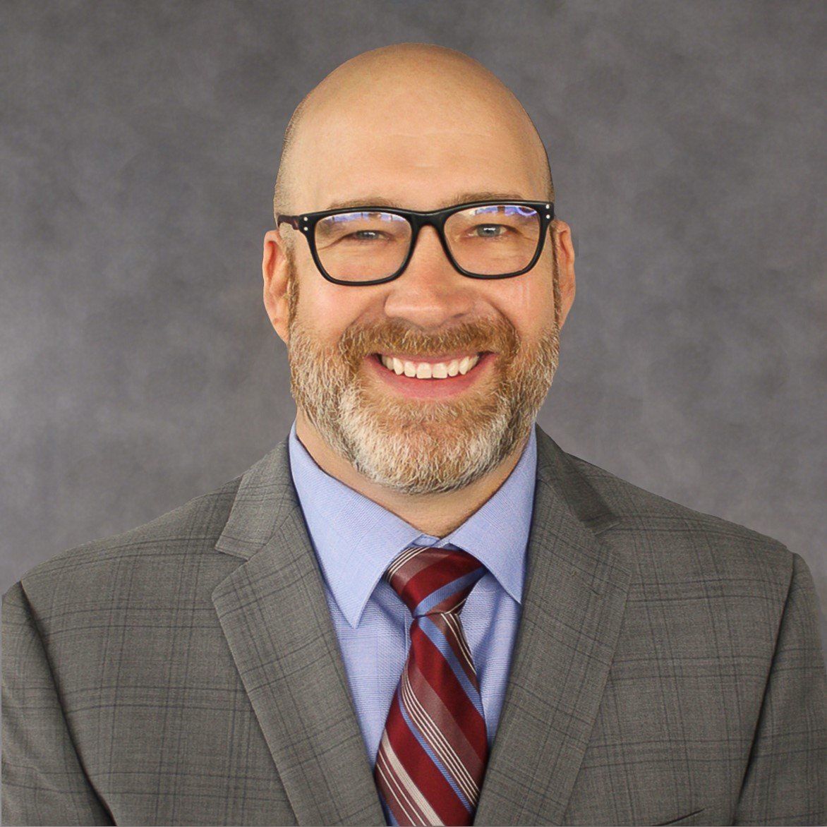 A man in a suit and tie is smiling for the camera.