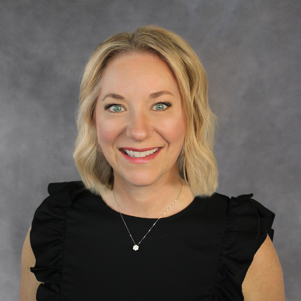 A woman wearing a black top and a necklace is smiling for the camera.