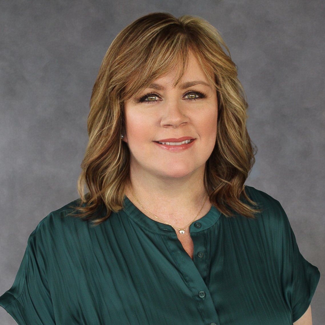 A woman in a green shirt is smiling for the camera.