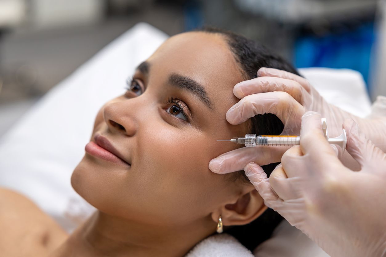 A woman is getting a botox injection in her forehead.