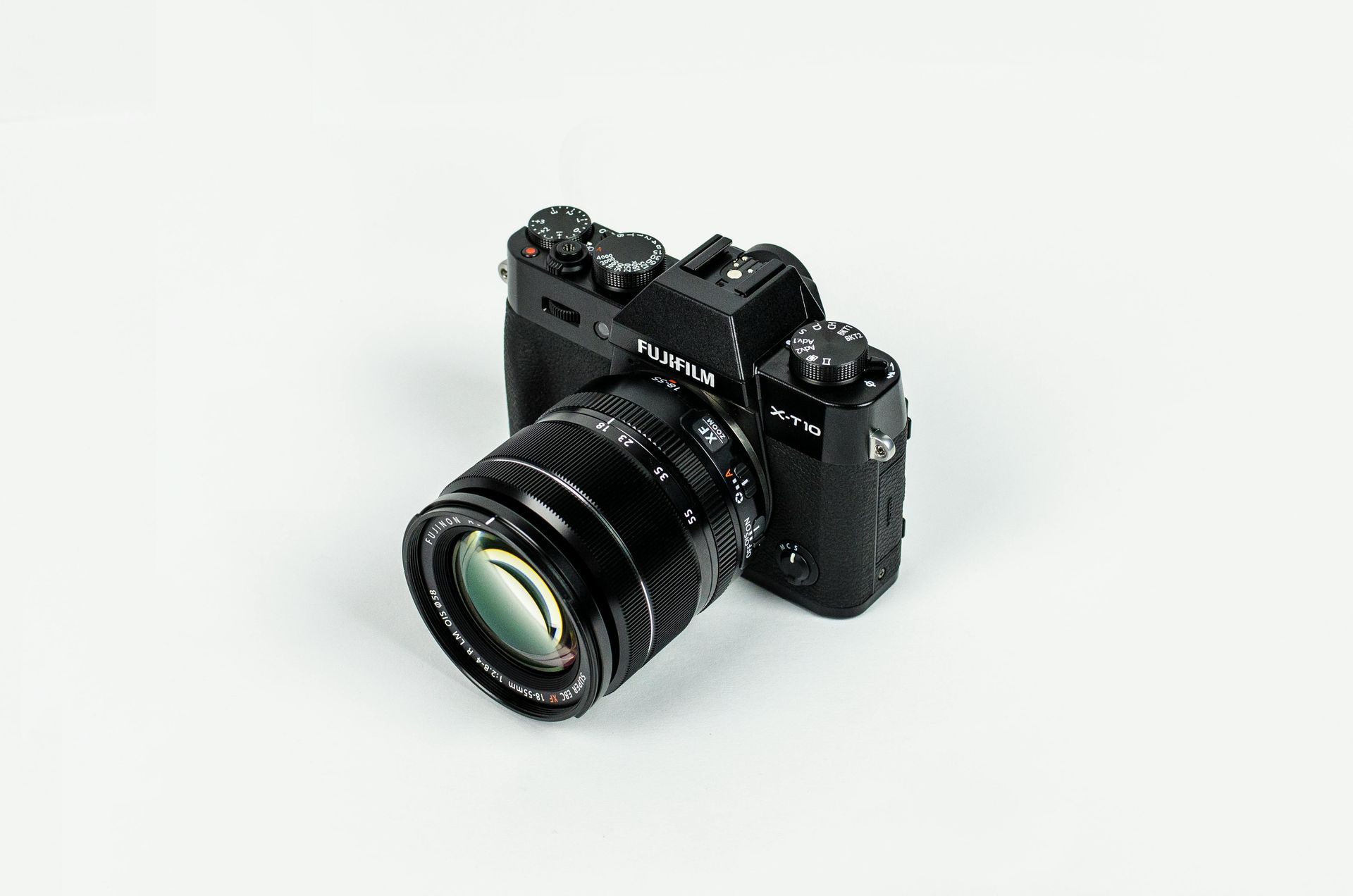 Black digital camera with lens on a white surface.