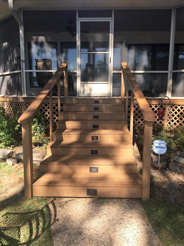 Wooden steps leading to a screened porch door. Handrails on each side.