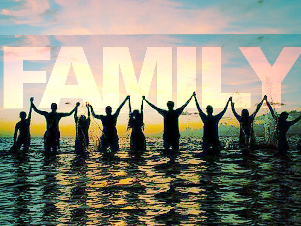 A group of people are standing in the water holding hands in front of the word family.