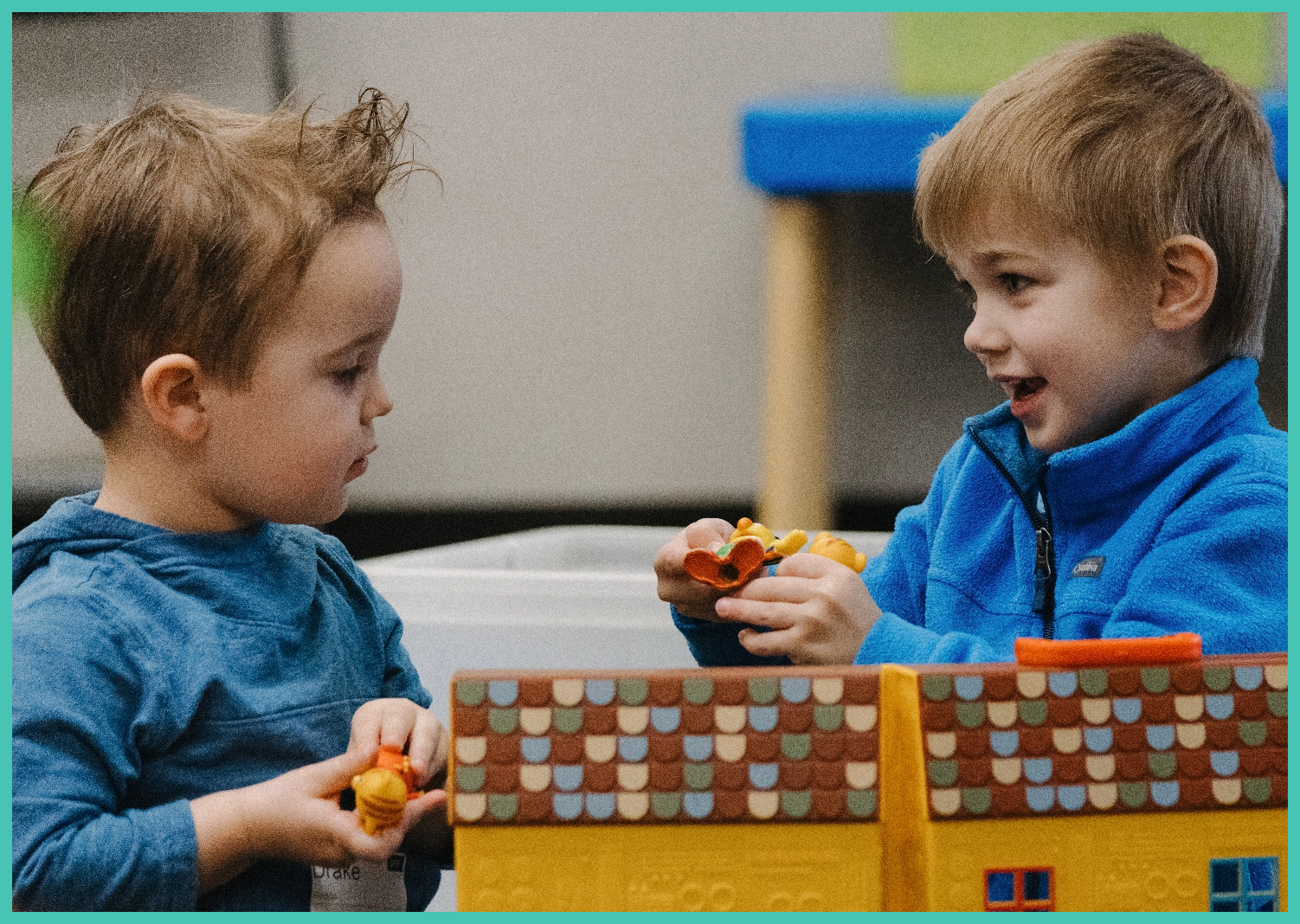 Two young boys are playing with a toy house.