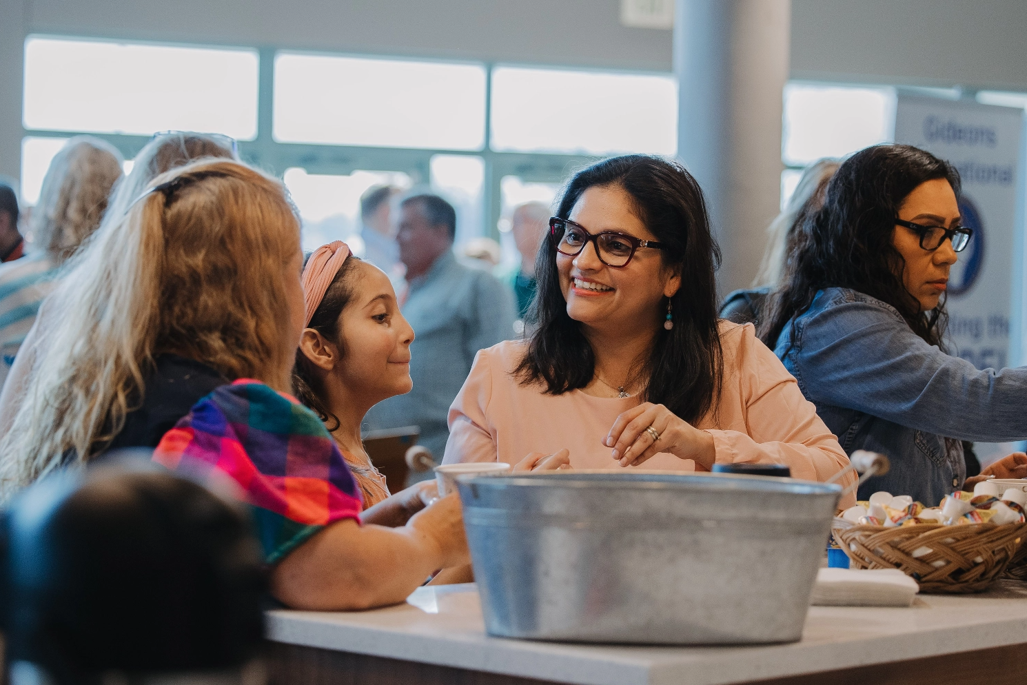 A group of women are sitting at a table talking to each other.