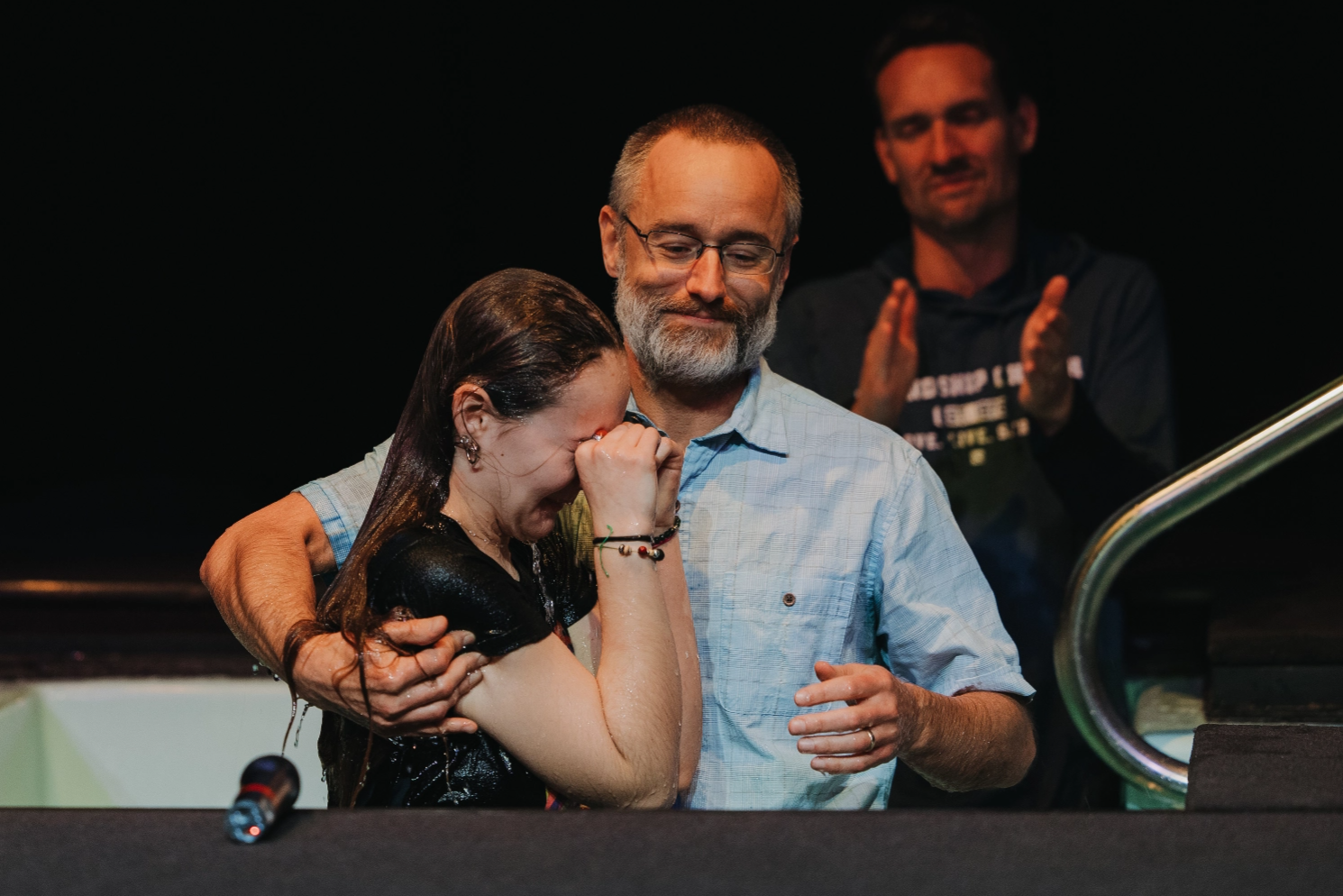 A man is hugging a woman who is being baptized.